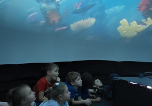 Dzieci leżą na podłodze wewnątrz kina sferycznego.