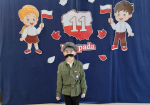 Chłopiec przebrany za Józefa Piłsudskiego pozuje do zdjęcia na tle dekoracji.