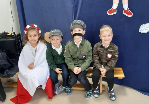 Dzieci siedzą na ławce i czekają na rozpoczęcie występu