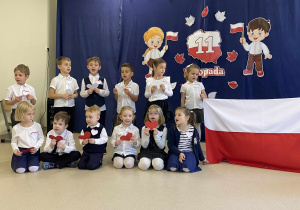 Dzieci śpiewają piosenkę trzymając flagę Polski