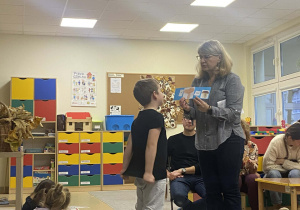 Chłopiec patrzy na ułożone przez siebie zdanie obrazkowo-wyrazowe pokazywane mu przez nauczyciela i próbuje je odczytać.