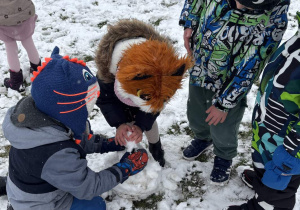 Dzieci dokładają śniegu do budowy bałwana.