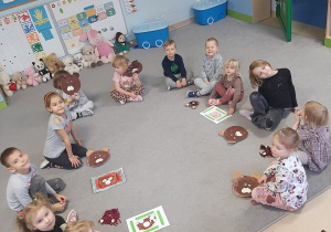 Dzieci siedzą w kole, przed nimi leżą prace plastyczne Misie