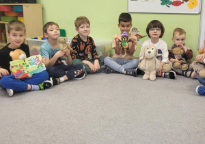 Dzieci siedzą na dywanie z misiami