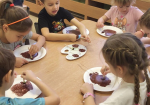 Dzieci siedzą przy stolikach i stemplują