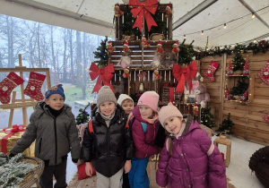 Dzieci pozują do zdjęcia na tle świątecznej dekoracji.