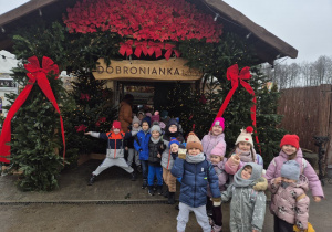 Dzieci pozują do zdjęcia przed wejściem do Dobronianki