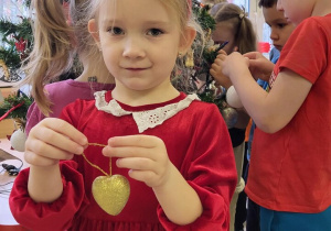 Dziewczynka w świątecznym stroju pokazuje złote serduszko