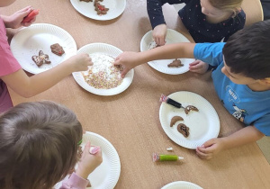 Dzieci ozdabiają pierniczki pisakami i posypką