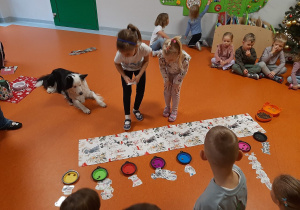 Dwie dziewczynki szukają na macie odpowiedniego obrazka przedstawiającego psa