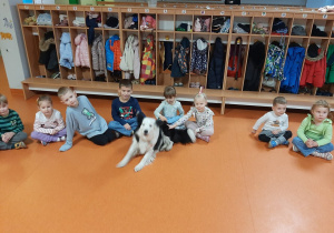 Dzieci siedzą na podłodze i głaszczą psa