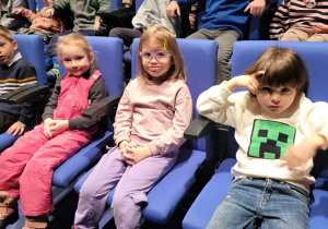 Dzieci siedzą na krzesłach w teatrze.