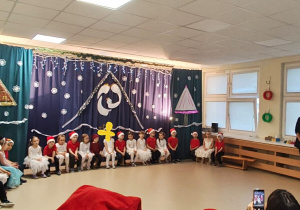 Dzieci siedzą na scenie podczas występu.