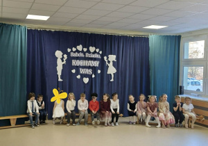 Dzieci siedzą na ławkach podczas występu