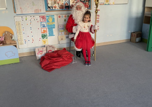 Dziewczynka pozuje w sali grupy Niebieskiej z postacią Świętego Mikołaja