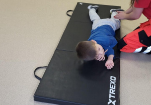 Chłopiec leży w pozycji bocznej bezpiecznej