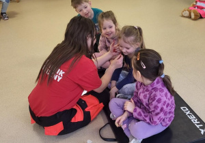 Dzieci mają naklejane plasterki przez ratowniczkę medyczną