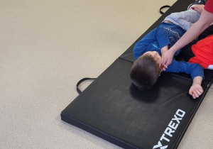 Dzieci oglądają instruktaż pozycji bocznej bezpiecznej