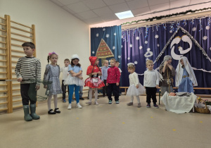 Grupa dzieci stoi na tle dekoracji.