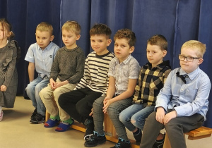 Na ławeczce siedzi sześciu chłopców.