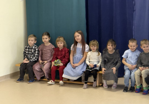 Dzieci siedzą na ławeczce.