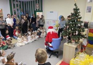 Dzieci siedzą w kole i słuchają opowieści Mikołaja