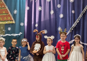 Gromadka dzieci stoi na tle dekoracji świątecznej