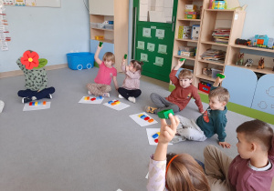 Dzieci unoszą do góry klocek w odpowiednim kolorze