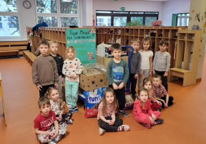 Dzieci stoją w szatni obok pudełek z karmą na zwierząt