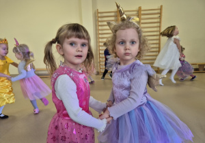 Dwie dziewczynki tańczą trzymając się za ręce.