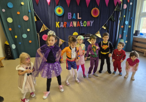 Grupa dzieci tańczy na tle dekoracji.