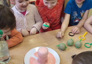 Dzieci oglądają eksperymenty z wodą, olejem, octem i sodą