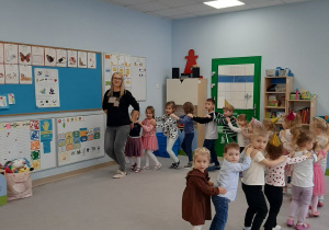Dzieci wraz z Panią nauczycielką tańczą do piosenki Jedzie pociąg z daleka