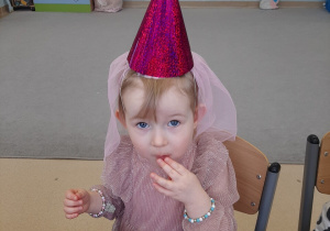 Dziewczynka siedzi przy stole i je ciasto