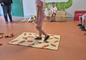 Dziewczynka idzie po macie z nadrukowanymi marczewkami.