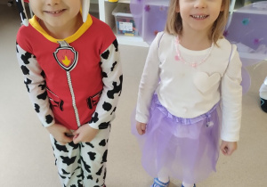 Dziewczynka i chłopiec uśmiechają się pozując do zdjęcia