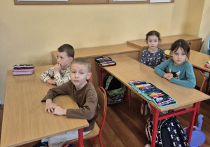 Czworo przedszkolaków siedzi w ławkach