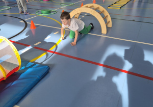 Chłopiec na czworaka pokonuje przeszkody na torze przeszkód