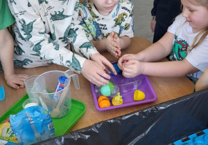 Dzieci bawią się zamrożonymi jajkami z dinozaurami