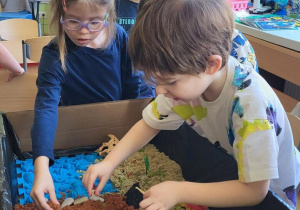 Dzieci kopią w pisku kinetycznym, aby odnaleźć dinozaury