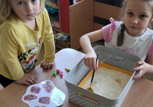 Dziewczynki szukają w kaszy szczątków dinozaurów