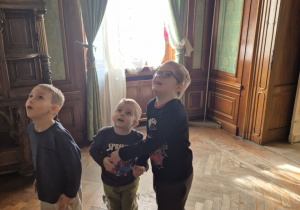 Trzech chłopców spogląda w górę w poszukiwaniu postaci z bajki o Muminkach