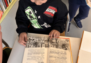 Chłopiec ogląda książkę w bibliotece.