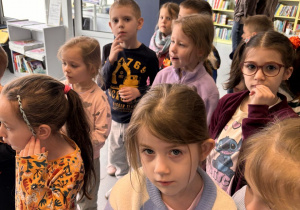 Dzieci znajdują się w Miejskiej Bibliotece i słuchają pani bibliotekarki nt. zasad obowiązujących na terenie biblioteki.