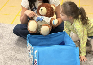 Prowadząca pokazuje pompę insulinową na misiu