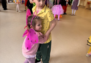 Starszy przedszkolak tańczy z młodszą przedszkolanką.