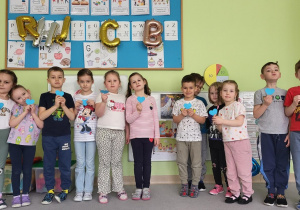 Dzieci pozują do zdjęcia z papierowymi sercami w dłoni