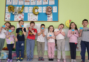 Dzieci pozują z niebieskimi serduszkami.