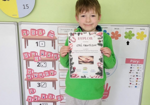 Chłopiec z dyplomem w rękach.