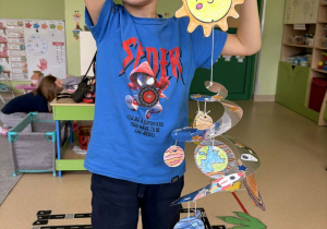 Chłopiec prezentuje pracę plastyczną.